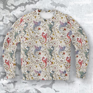 May include: Crew neck sweatshirt with a repeating pattern of colorful dragons, vines, and stars on an off-white background. The dragons are in shades of red, blue, and green. The sleeves and body are covered in the design.