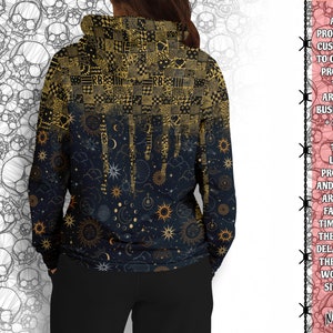 May include: A black hoodie with a gold and white celestial print. The print features stars, moons, and suns. The hoodie has a drawstring hood and a kangaroo pocket.