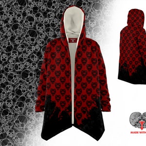 Pode incluir: Casaco vermelho com capuz e padrão de caveira. O casaco tem um design longo e fluido e uma bainha preta. A parte de trás do casaco tem um design de caveira preta. O texto "Made with Love" está impresso na parte inferior da imagem.