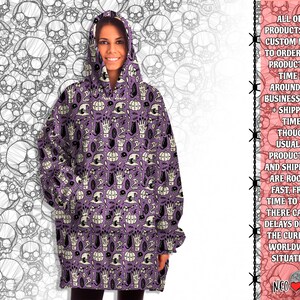 May include: Purple oversized hoodie with a spooky Halloween print featuring skulls, pumpkins, hands, and other spooky elements. The print is repeated all over the hoodie.
