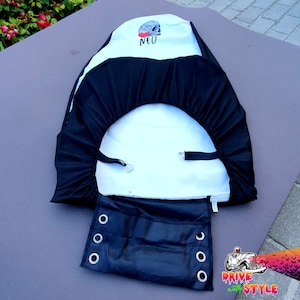 May include: Black and white car seat cover with a skull graphic and the word "NEO" printed on it. The cover has a black elastic band and a black flap with grommets.