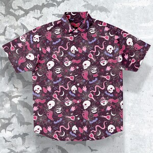 Puede incluir: Camisa de manga corta con botones, con un fondo morado oscuro y un patr&oacute;n repetido de calaveras blancas, manos rosas, botellas de pociones y telara&ntilde;as. La camisa tiene un cuello cl&aacute;sico y una parte delantera abotonada. El dise&ntilde;o es de tem&aacute;tica de Halloween.
