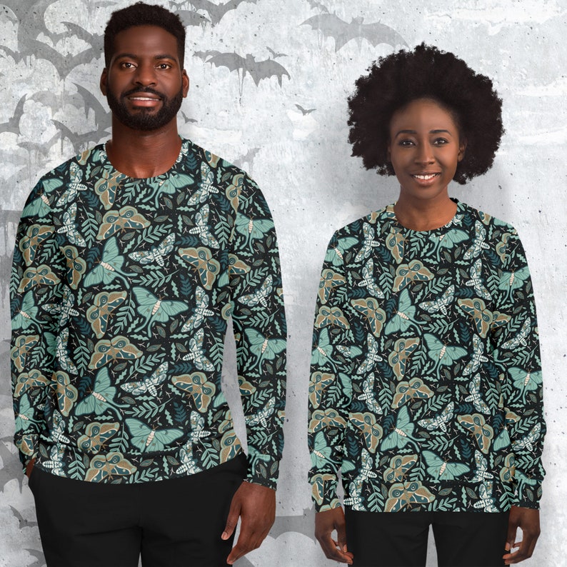 May include: Two people wearing long-sleeved sweatshirts with a repeating pattern of green and brown moths on a black background.