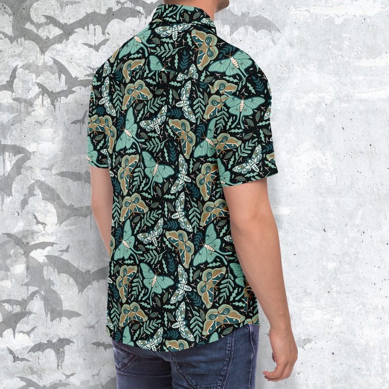 Puede incluir: Una camisa de manga corta con botones, fondo negro y un patr&oacute;n repetido de polillas verdes y marrones y hojas.