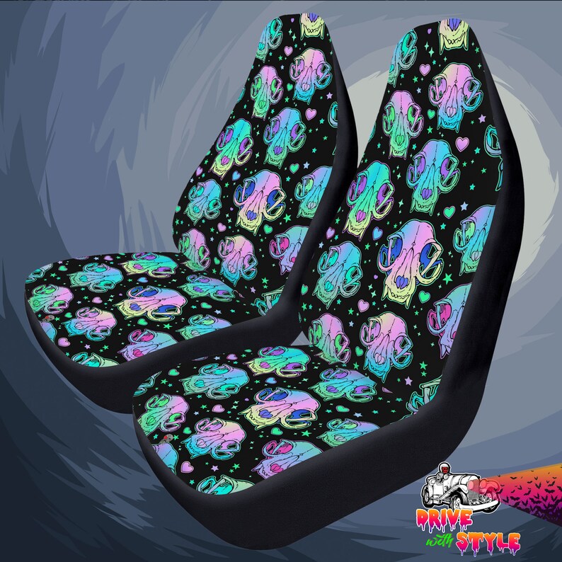May include: Two black car seat covers with a colorful skull and heart pattern. The pattern features pastel pink, blue, green, and yellow colors on a black background.