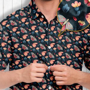 May include: A dark blue short-sleeved button-down shirt with a repeating pattern of butterflies and flowers. The shirt has a button-up collar and a pocket on the left side.