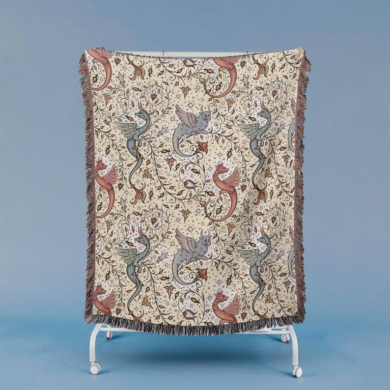 May include: A woven tapestry throw blanket with a cream background and a repeating pattern of stylized dragons in shades of blue, red, and pink. The dragons are depicted with wings and tails, and they are surrounded by intricate floral designs.