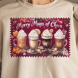 Peut inclure: Un sweat-shirt beige avec un motif festif. Le motif représente quatre tasses de café avec de la crème fouettée, des biscuits et des cannes en sucre, avec le texte "Merry Mugs of Cheer" sur un fond bordeaux.