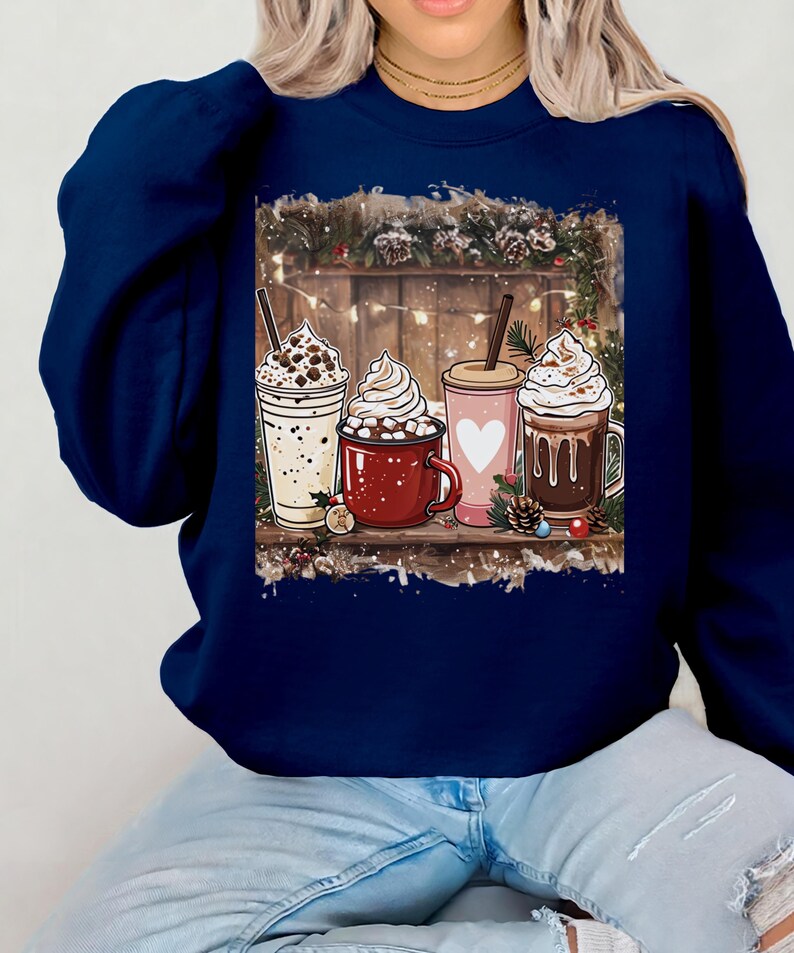 Peut inclure: Sweat-shirt bleu marine avec un motif de quatre boissons chaudes festives, chacune garnie de cr&egrave;me fouett&eacute;e. L'image comprend une &eacute;tag&egrave;re en bois et des d&eacute;corations de No&euml;l. Un style d&eacute;contract&eacute; et confortable.