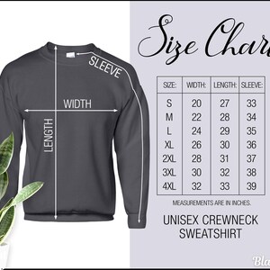 Peut inclure: Un sweat-shirt ras du cou unisexe gris fonc&eacute; avec un tableau des tailles. Le tableau indique les mesures en pouces pour la largeur, la longueur et la longueur des manches, allant de la taille S &agrave; 4XL. Le texte "Size Chart" est en haut.