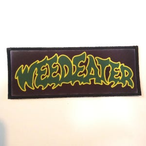 May include: A dark purple patch with the band name "WEED EATER" in green letters with a yellow outline.