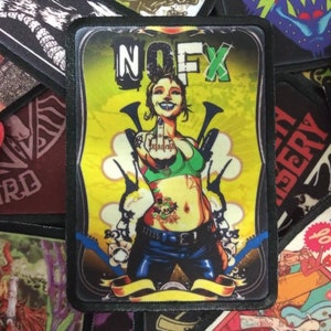 May include: A black and white embroidered patch with a cartoon woman giving the middle finger. The woman is wearing a green bra and blue jeans. The patch has the text "NOFX" in green and yellow letters.