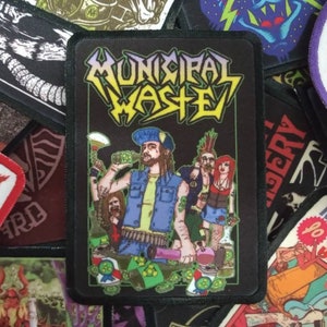 Può includere: Una toppa ricamata nera e gialla con il testo "Municipal Waste" in grassetto. La toppa presenta un'immagine di un membro della band con la barba e un bandana verde, che tiene una bottiglia di birra e un microfono.
