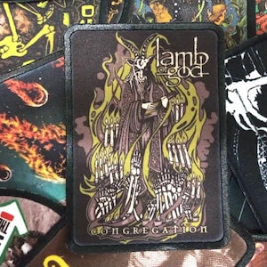 Può includere: Toppa in bianco e nero con una grafica di una figura cornuta in una veste con fiamme e il testo "Lamb of God Congregation".