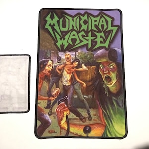 Puede incluir: Un parche blanco y negro con un logotipo verde y blanco que dice "Municipal Waste". El parche presenta un gráfico de una figura de zombi con una mano ensangrentada que se extiende.
