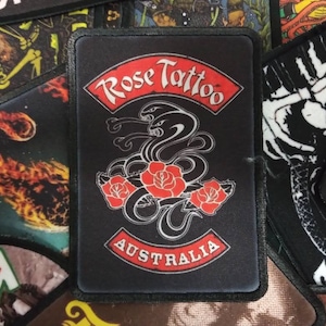 May include: Black and red embroidered patch with the text "Rose Tattoo Australia" and a design of three snakes with roses around them.