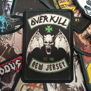 May include: Black and green embroidered patch featuring a winged demon, the text "Overkill" and "Est. 1980 New Jersey".