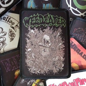 Può includere: Una collezione di toppe di band in bianco e nero con vari nomi di band, tra cui "Weed Eater", "Foo Fighters" e "Megadeth".