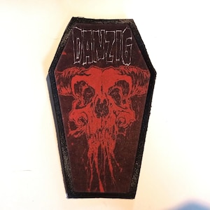 May include: Black and red coffin-shaped patch with the word "DANZIG" in white lettering and a red skull with horns graphic.