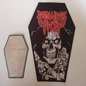 May include: Black and red embroidered patch shaped like a coffin with a skull and crossbones image and the text "POWER TRIP".
