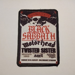May include: A black and white patch featuring a skull and crossbones graphic. The text "The Kings of Rock" is above the skull. The text "Black Sabbath" is in red and white. The text "Motörhead" is in black and white. The text "Twisted Sister" is in red and white. The text "Diamond Head" is in black and white. The text "Anvil" is in red and white. The text "Judas Priest" is in black and white. The text "Sunday 28th August - Dalymount Stadium" is in black and white.