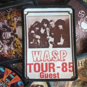 May include: A white and red embroidered patch with a band photo and the text "W.A.S.P. TOUR-85 Guest".
