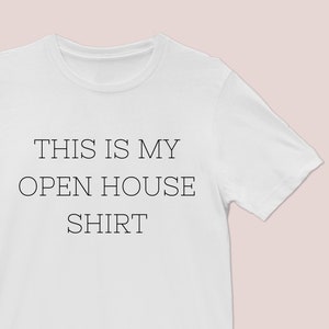 以下が含まれることがあります： 黒い文字で「This is my open house shirt」とプリントされた白いTシャツです。