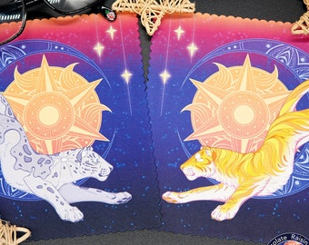 May include: Two playing cards with a blue and purple background. The cards feature a white and gray snow leopard and a yellow and orange tiger jumping in front of a sun and stars. The cards have a scalloped edge and the text "Chocolate Raisin Fury" is on the bottom right corner.