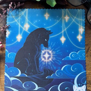 May include: A blue square art print with a black wolf silhouette looking at a glowing star. The background is a blue gradient with stylized clouds and hanging stars. The print has a scalloped edge.