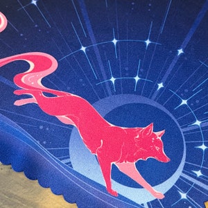 Puede incluir: Un zorro rosa corriendo sobre un fondo azul con una luna creciente y estrellas. El zorro est&aacute; estilizado y tiene una cola larga y fluida.