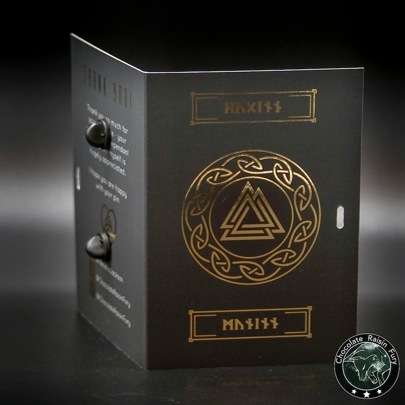 May include: A black card with gold lettering and a gold symbol. The symbol is a circle with a triangle inside. The text on the card says "Haxix" and "Chocolate Raisin Fun".