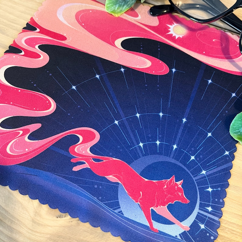 Puede incluir: Un pa&ntilde;o de limpieza de microfibra azul y rosa con una ilustraci&oacute;n estilizada de un zorro rojo corriendo sobre una luna creciente con un fondo estrellado.