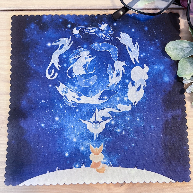 May include: A blue and white mousepad with a design of a constellation of stars and a group of stylized foxes. The foxes are arranged in a circle around a central star.
