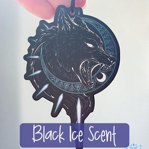 May include: Black car air freshener with a wolf howling at the moon design. The text "Black Ice Scent" and "Leathery / Musky" are printed below the image.