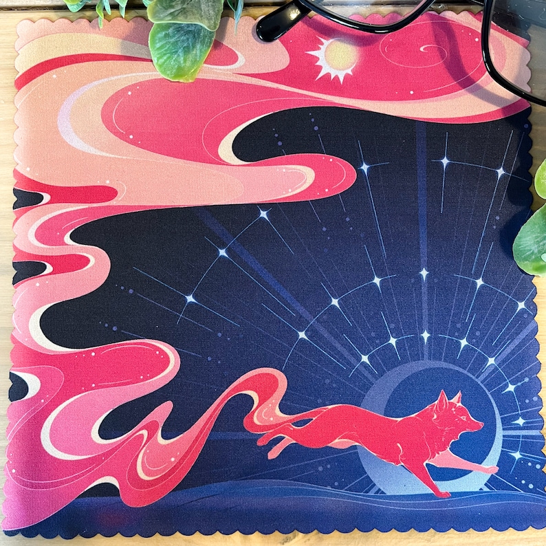 Puede incluir: Un pa&ntilde;o de limpieza de microfibra con estampado rosa y azul con un zorro rojo corriendo por un cielo nocturno estrellado. El zorro corre hacia un sol brillante.
