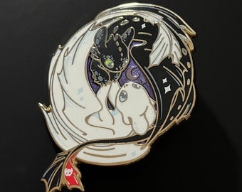 Op de afbeelding: Een zwart-witte emaille pin met een yin yang-ontwerp met een zwarte draak en een witte draak. De draken kijken elkaar aan en hun staarten zijn met elkaar verweven. De pin heeft een gouden afwerking en een rode accent op de staart van de zwarte draak.