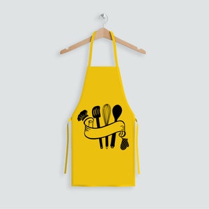 May include: A yellow kitchen apron with a black design of kitchen utensils, a chef's hat, and a banner.
