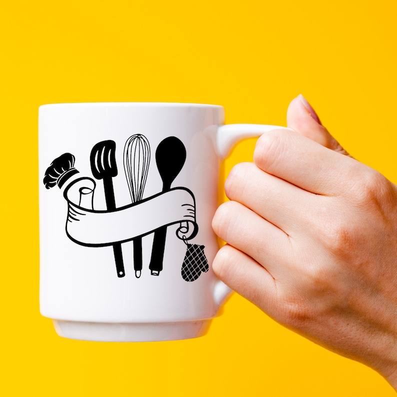 May include: White ceramic mug with a black design of kitchen utensils, including a whisk, a spatula, and a spoon, tied together with a ribbon. The design also includes a chef's hat and a pot holder.