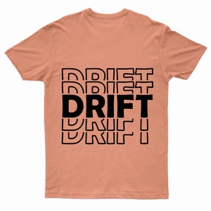 Puede incluir: Una camiseta de color melocot&oacute;n con la palabra "DRIFT" impresa en letras negras apiladas unas sobre otras.