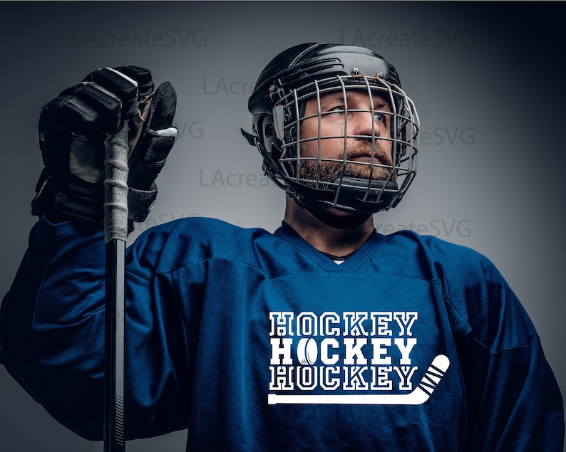 May include: A person in a blue hockey jersey and a black helmet with a cage. The jersey displays the word "HOCKEY" in white, stacked three times, with a hockey puck and stick graphic.