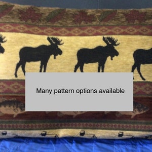 May include: A decorative throw pillow with a brown, beige, and red patterned design featuring silhouettes of moose and fish. The text "Many pattern options available" is printed on the pillow.