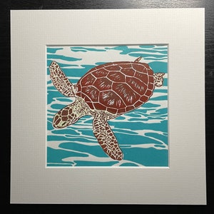 Op de afbeelding: Een bruine en witte zeeschildpad zwemt in turquoise blauw water. De schildpad is afgebeeld in een houtsnede stijl.