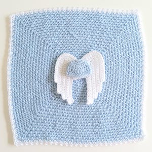 May include: A handmade, square baby blanket in light blue with a white crocheted border. The blanket features a white crocheted angel wing design and a small blue crocheted hat. The blanket is approximately 12 inches square.