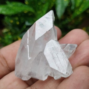 Puede incluir: Un grupo de cristales de cuarzo transparentes con una textura rugosa y natural. Los cristales están agrupados en forma de pirámide.