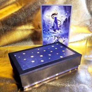 Una caja. Me envías el tamaño de tu baraja. La fabrico a mano para que se ajuste perfectamente a tu baraja. Tú eliges los colores. Cada caja es única.