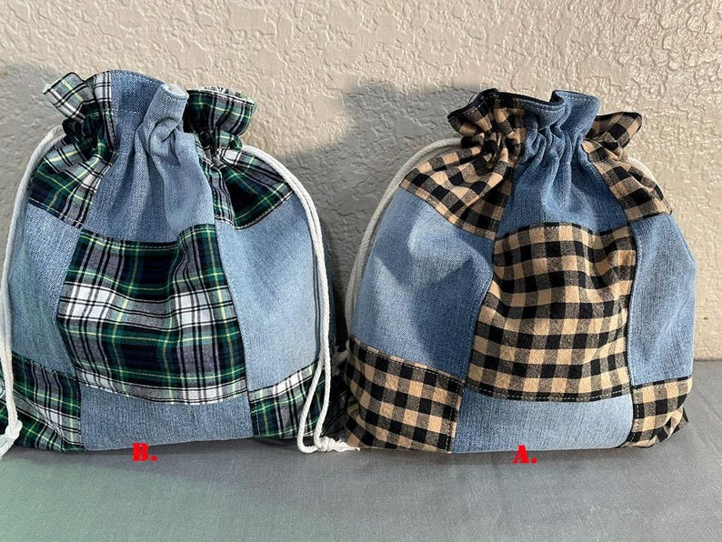 May include: Two drawstring bags with a patchwork design. The bags combine denim with plaid fabric in green, black, and tan. Each bag has a white drawstring closure. The bags are labeled with the letters "A" and "B".