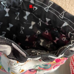 Pu&ograve; includere: Primo piano dell'interno di una borsa in tessuto. La fodera interna &egrave; nera con un motivo a farfalla bianco. Il tessuto esterno presenta un colorato design floreale e paisley. &Egrave; visibile una cinghia a scacchi rossi e bianchi.