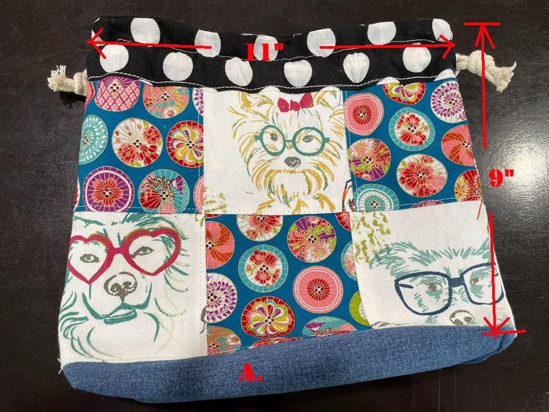 Pu&ograve; includere: Un sacco con coulisse patchwork, alto circa 23 cm e largo 2,5 cm, con illustrazioni di cani con gli occhiali. La borsa ha una base in denim, una parte superiore a pois bianchi e neri e una chiusura con coulisse.