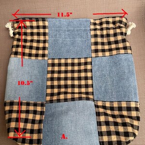 May include: Patchwork tote bag with a denim and black and tan plaid design. The bag is 11.5 inches wide and 10.5 inches tall. The bag has a drawstring closure with white tassels on each side.