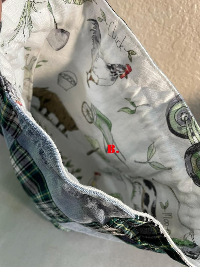 May include: A fabric bag with a patchwork design. The exterior features denim and green plaid fabric. The interior lining is white with a farm animal print, including a chicken, cow, and pig. The word "Chick" is visible.